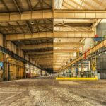 Expansive interior of an industrial warehouse showing steel beams, high ceilings, and ample space.